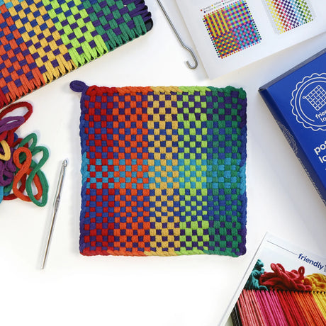 Potholder Loom Pro with colorful woven cotton loops, metal hooks, and illustrated instructions for making potholders.