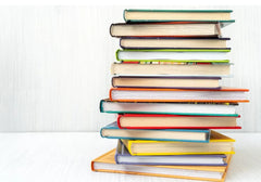 Stack of colorful hardcover books on a white wooden surface