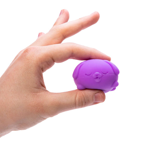 Hand holding a small purple squishy dog toy with a puckered face NeeDoh Teenie Funky Pup squeeze toy.