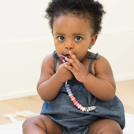 Baby holding pacifier attached to Pacifier Clip | Bright Multi with colorful silicone beads and stainless steel clip.