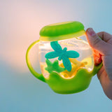 Mini Sensory Jar | Green glowing sensory jar with colorful butterfly and star shapes held in a hand