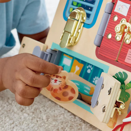 Child’s hand playing with a colorful Lock & Learn Playboard featuring locks, doors, and imaginative activities.