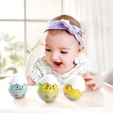 Baby playing with three colorful wobble rattles featuring playful faces on a high chair tray in bright room