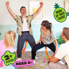 Four adults playing It’s Bananas party game with monkey tails, having fun and warming up their thighs indoors
