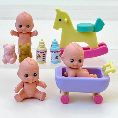 Set of small baby dolls with toy bottles, teddy bears, rocking horse, and purple bathtub on wheels for playtime fun