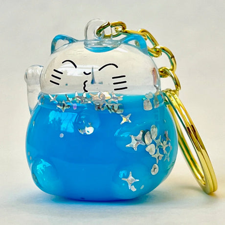 Colorful Cat Floaty KeyChain with blue liquid and star-shaped glitter, attached to a gold keyring for easy clipping.