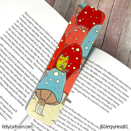 Frog & Mushrooms Bookmark featuring a cute frog drinking juice amid colorful mushrooms with glossy finish on thick paper.