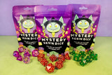 Three Halloween Mystery Dice Bag packages with colorful polyhedral dice displayed on a table