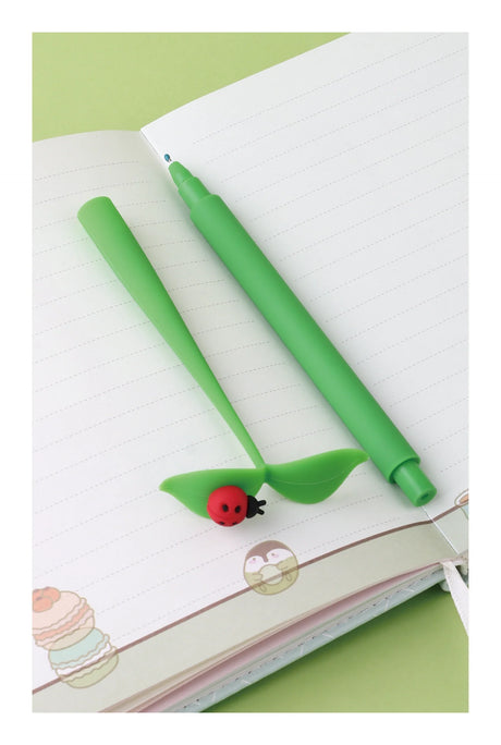 Bug on Leaf Wiggle Gel Pen with green leaf cap and ladybug detail, smooth fine tip black gel ink pen on notebook.