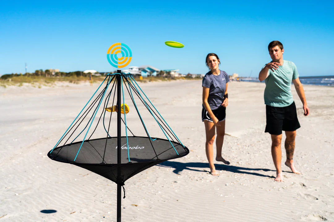 Waboba Hitman disc target game set on beach with two people playing and aiming at the adjustable height cage and bullseye topper