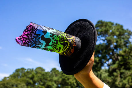 Hand holding colorful Waboba Throwback velcro AIRLYFT glider paddle against blue sky outdoors.
