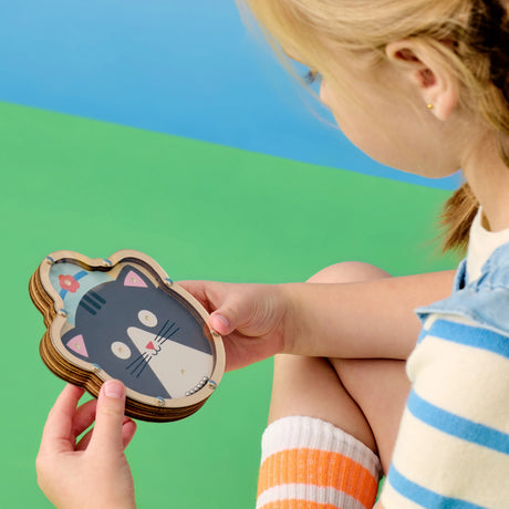 Child playing with a Double Sided Tilt & Roll Puzzle featuring a cute cat design on FSC plywood.