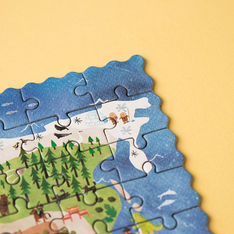 Close-up of puzzle pieces from the 100pc Discover the World Pocket Puzzle showing ocean and forest illustrations.