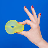 Hand holding a soft, yellow squishy stress loop against a bright blue background