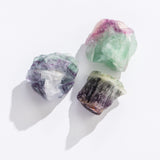 Rock | Rough Rainbow Fluorite displaying natural multi-colored green, purple, and clear crystal formations on a white background.