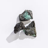Rock | Rough Emerald Quartz featuring natural green emerald crystals embedded in rough dark quartz stones on a light background