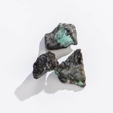 Rock | Rough Emerald Quartz featuring natural green emerald crystals embedded in rough dark quartz stones on a light background