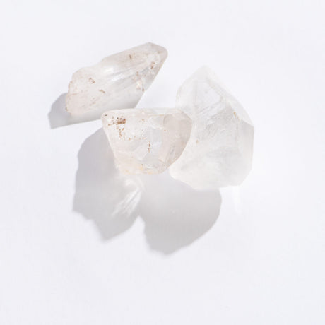 Three clear quartz point crystals with natural imperfections on a white background, Rock | Clear Quartz Point.