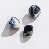 Rock | Tumbled Sodalite showing three polished blue and white stones on a white background with soft shadows.