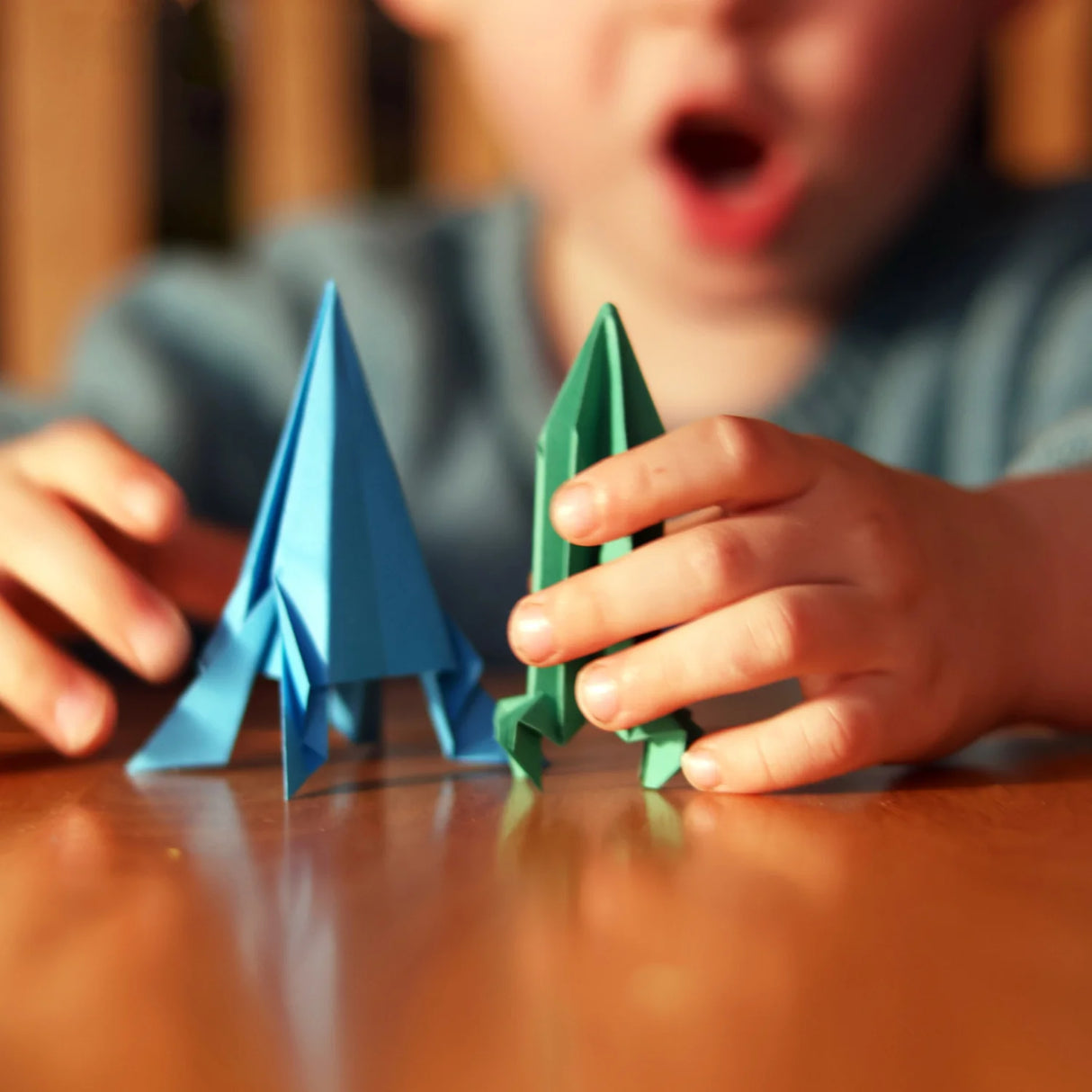 Child holds colorful paper rockets on table, excited to launch and play with flying paper rocket kit.