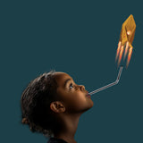 Young child blowing through a straw to launch a glowing paper rocket against a dark background