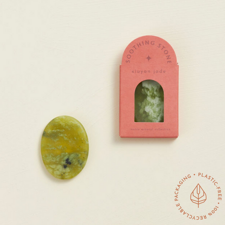 Soothing Stone | Xiuyan Jade oval matte stone with soft green patterns next to pink eco-friendly box packaging.