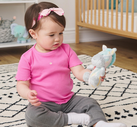 Baby holding a pastel-colored plush animal Safari Friends Stick Rattle designed for little hands.
