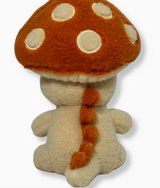 Plush mushroom character with orange cap and white spots viewed from behind showing small arms and tail details