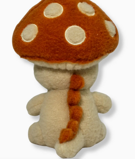 Plush mushroom character with orange cap and white spots viewed from behind showing small arms and tail details