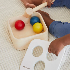 Punch & Drop Bin wooden toddler toy with child using a mallet to tap colorful balls through holes