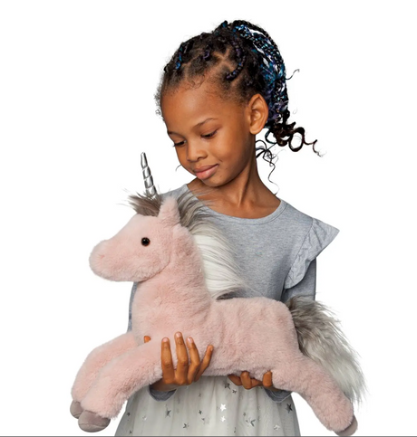 Young girl holding Unicorn Mauve Esme plush with dusty rose coat and silvery horn against white background.