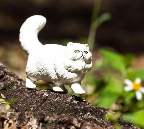 Persian Cat figure with fluffy white coat, bushy tail, green eyes, and flattened face posed on tree bark outdoors.