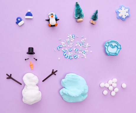 Sensory Pack | Winter with cloud clay, penguin, snowman pieces, mini trees, pom poms, and winter-themed sensory toys on purple background.