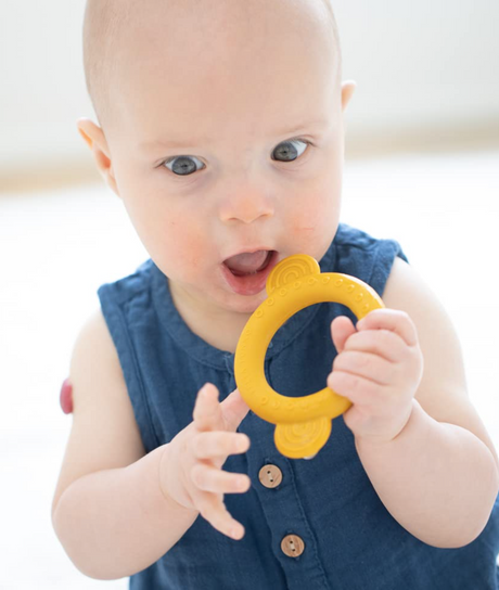 Baby holding and mouthing the yellow Rattle Teether | Monkey designed for sensory play and teething relief.