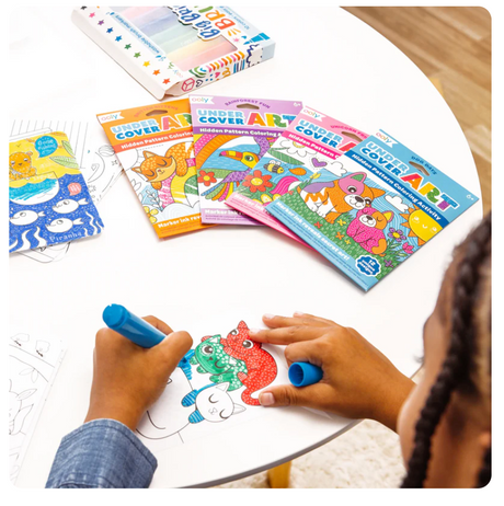 Child coloring animal illustrations from Undercover Art | Rainforest Fun hidden pattern activity set on a round white table.