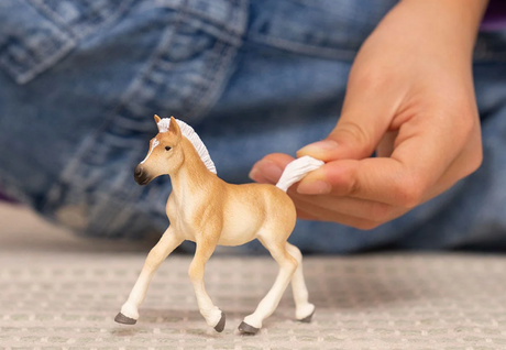 Horse Haflinger Foal model being held by hand, showing detailed prancing foal with white mane and tail.