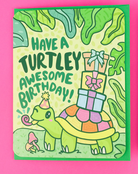 Turtley Awesome Birthday Card featuring a smiling turtle with birthday gifts and party hat surrounded by greenery.
