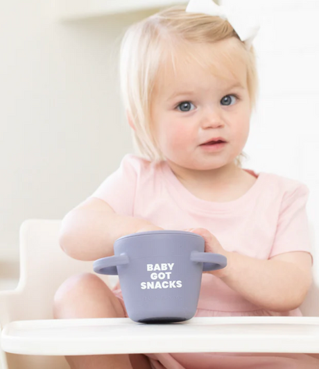 Happy Snacker | Baby Got Snacks snack cup held by toddler in high chair, perfect for self-feeding and snack time.