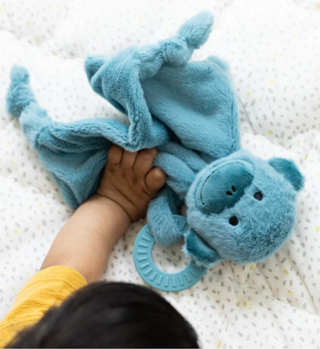 Baby holding Teether Buddy | Milo the Monkey plush toy with teething ring for soothing gums and cuddling.