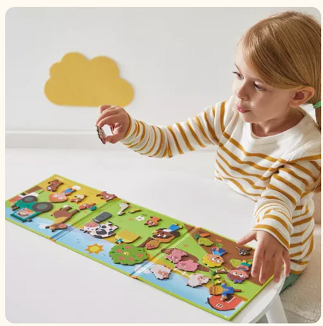 Child playing with MagnetiStories | Farm magnetic book featuring farm animals and vegetables on a colorful background.