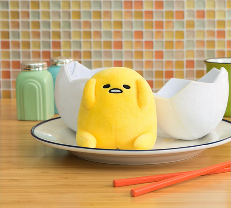 Gudetama in Eggshell plush showing a yellow yolk character sitting in front of a soft white eggshell on a plate.