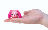 Perk Ups! small pink puppy toy with floppy ears sitting on a hand, ears designed to flap when squeezed.