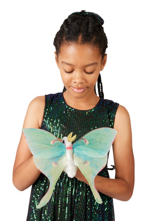 Girl wearing a sequined dress holding a large Luna Moth Finger Puppet with delicate green wings.