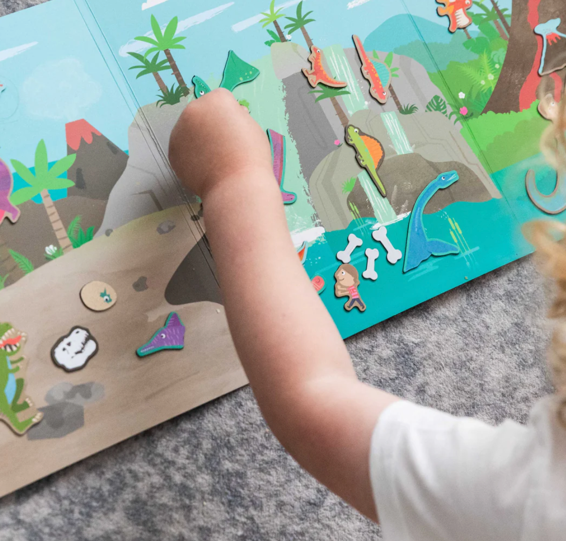 Child playing with Magna Carry | Dino World magnetic puzzle featuring dinosaurs, volcano, and waterfall scene.