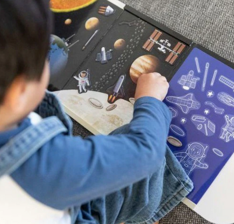 Child playing with Magna Carry | Space Explorer magnetic space scene featuring rockets, planets, and astronauts on a fold-out playset.