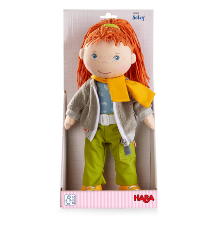 Soft Doll | Soley with red hair, cozy fleece jacket, yellow scarf, and green pants in packaging by HABA.