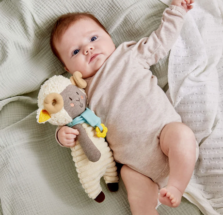 Baby holding Woolbert the Ram Pacifier Holder with soft teething flower and cuddly ram design for comfort.