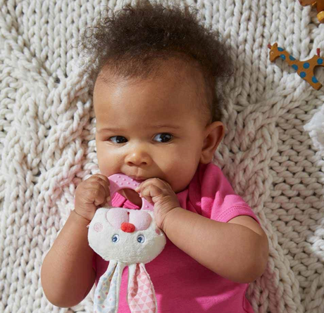 Baby chewing on Chomp Champ Bunny Teether with embroidered face and dimpled plastic ring for teething relief.