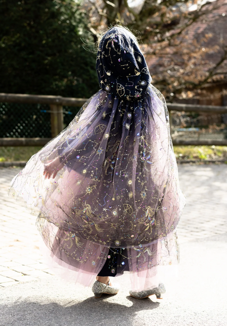 Child wearing a flowing dark purple cloak with shimmering celestial embroidery and a roomy hood outdoors on a sunny day