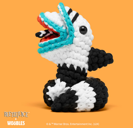 Handmade crochet sandworm with black, white and blue stripes and two heads against orange background